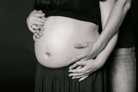 Hands of men and women on pregnant belly