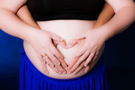 Hands of men and women on pregnant bellyの写真素材