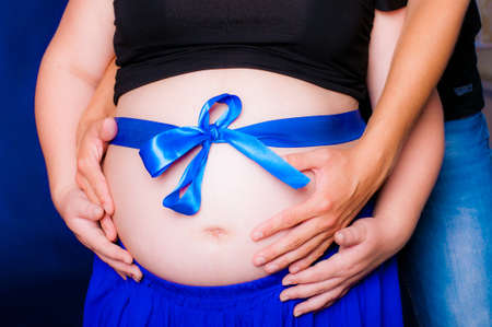 Hands of men and women on pregnant bellyの写真素材