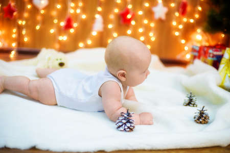 Little baby with gifts at Christmas treeの写真素材