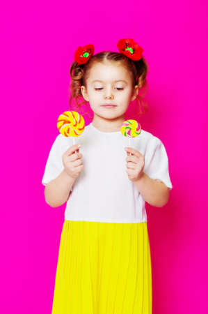 Little girl in a beautiful dress with a big candy lollipop in handsの写真素材