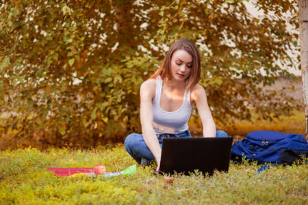 Student girl on green grass with computer
