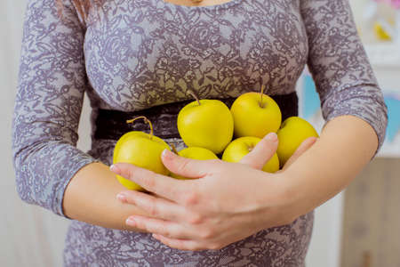 Pregnant woman with green apples in her handsの写真素材