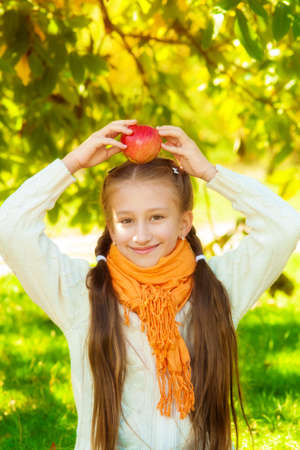 Schoolgirl with apples in autumn parkの写真素材