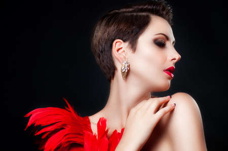 Young beautiful girl in a dancing suit with red feathers. Makeup. Fashion. Beautiful model with fashion make-upの写真素材