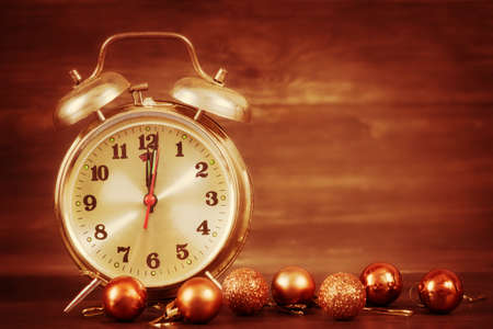Christmas toys baubles and retro alarm clock on wooden background
