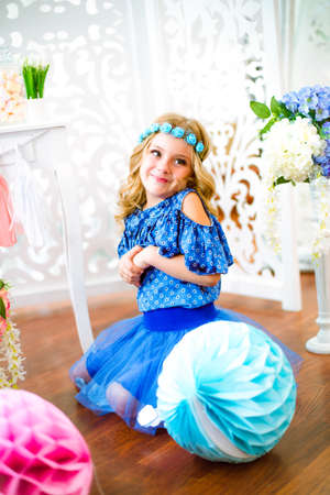 A portrait of a beautiful little girl laughing in a studio decorated many color balloonsの写真素材