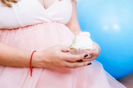 Expecting mother eating pink cupcake on a baby shower partyの写真素材