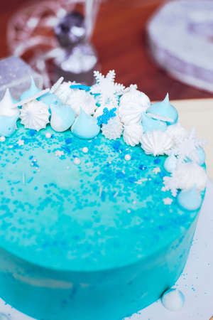 Blue birthday cake with small meringues and white snowflakesの写真素材