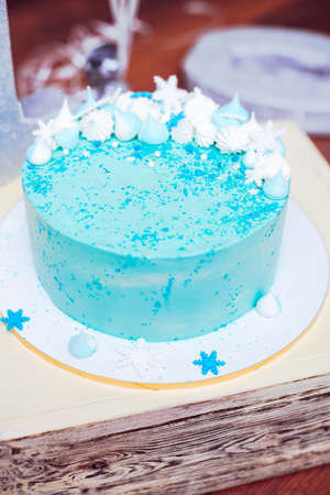 Blue birthday cake with small meringues and white snowflakesの写真素材