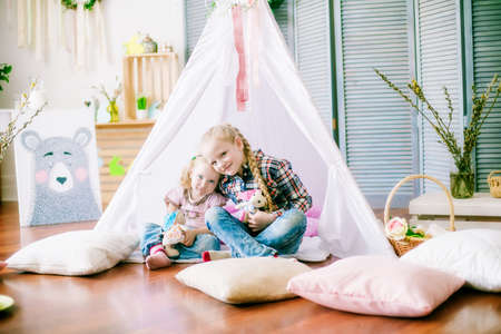 Little cute sister girls are preparing for Easter celebration. Children having fun with Easter decoration sitting on the floor at home.の写真素材