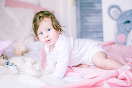 Cute girl, a baby in white body on the pink bedprincess at home