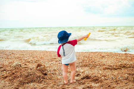 Baby boy playing at sea. Happy boy enjoys life on summer beachの写真素材