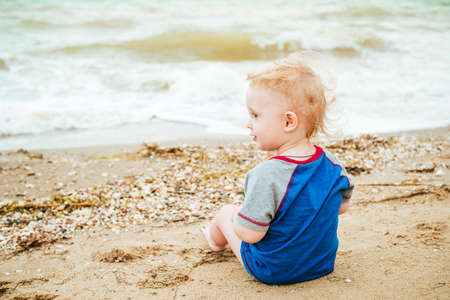 Baby boy playing at sea. Happy boy enjoys life on summer beachの写真素材