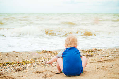 Baby boy playing at sea. Happy boy enjoys life on summer beachの写真素材