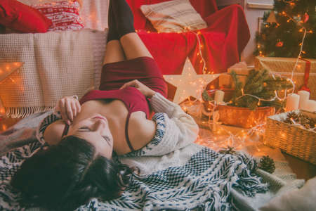 woman at home enjoying by Christmas tree.の写真素材