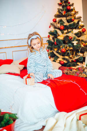 Little girl in pajamas at Christmas morning.Merry Christmas.Little girl rejoices to the Christmas giftの写真素材