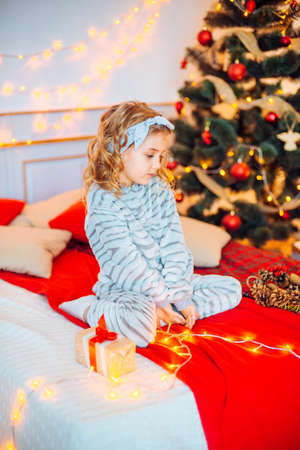 Little girl in pajamas at Christmas morning.Merry Christmas.Little girl rejoices to the Christmas giftの写真素材