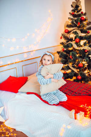 Little girl in pajamas at Christmas morning.Merry Christmas.Little girl rejoices to the Christmas giftの写真素材