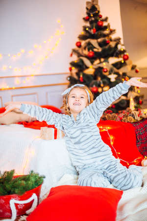 Little girl in pajamas at Christmas morning.Merry Christmas.Little girl rejoices to the Christmas giftの写真素材