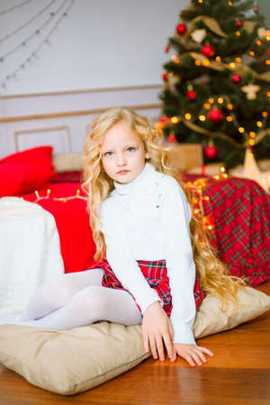 Little girl with blond long hair at Christmas morning. Merry Christmas. Little girl rejoices to the Christmas giftの写真素材