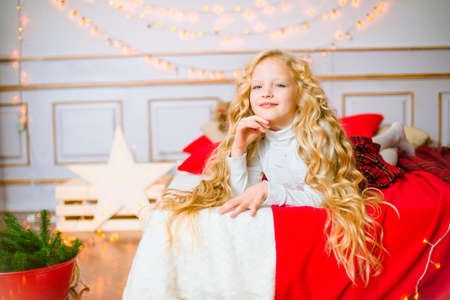 Little girl with blond long hair at Christmas morning. Merry Christmas. Little girl rejoices to the Christmas giftの写真素材