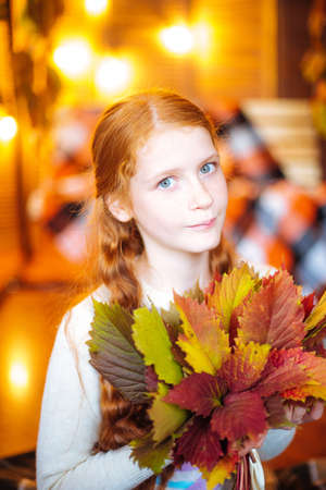 Red-haired teenager girl with yellow leavesの写真素材