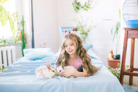 Little cute girl with little bunnies and Easter decor at homeの写真素材