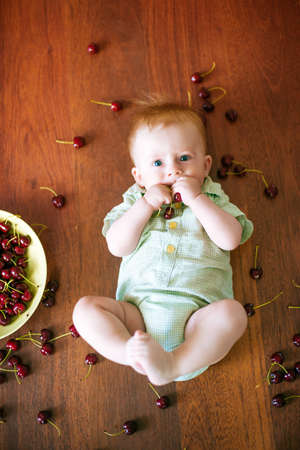 little baby with cherry in hands