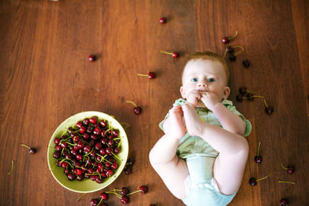 little baby with cherry in handsの写真素材