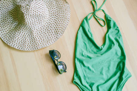 Bright trendy bikinis on a wooden background, as well as a straw hat with wide brim and sunglasses. Fashionable beachwear and accessories.の写真素材