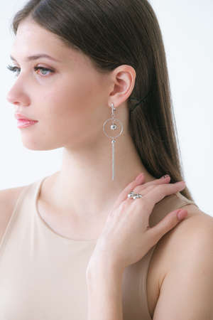 Trendy silver earrings bracelet and ring on a beautiful young girl with long dark hair. Beauty and fashionの写真素材