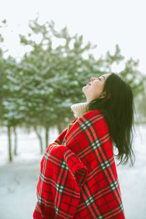 Young cute girl with durk hair in red scarf has fun in snowy weather in winter in the park. Life...