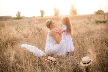 Mother and daughter in a wheat field at sunset. The concept of a happy family.の写真素材