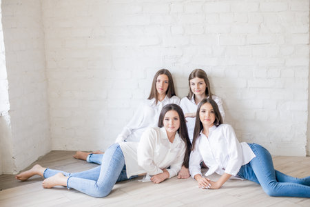 Pretty teenage girls models in trendy jeans and white shirts in the studio against the background of...