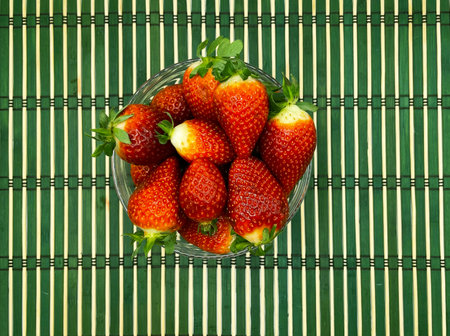 Sweet juicy strawberries on a green background, in a container, on the back, strawberries on a saucer, strawberries in a scatteringの写真素材