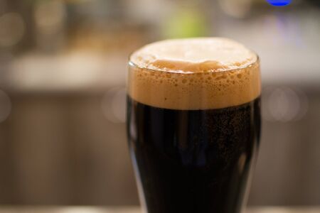Glass - pint- of dark beer with foamの写真素材