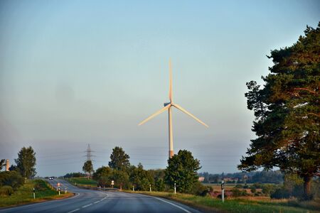 Road with view to wind turbines installations for green energy in the countryside.