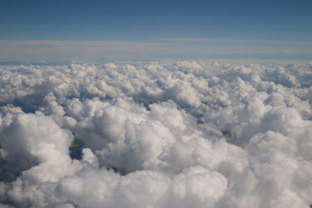 Cloudscape featuring fluffy cumulus clouds with a hazy blue background of sky.