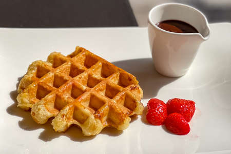 Belgian waffles topped with strawberries, and hot chocolate.の写真素材