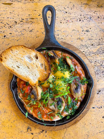 Shakshuka breakfast of fried eggs and tomatoes in a pan. vertical view from aboveの写真素材