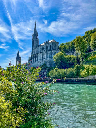 Beautifull Sanctuary in Loudres with river lined with green trees at sunny day, vertical photoの写真素材