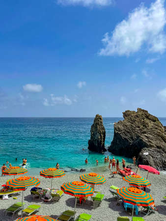 Cinque Terre beach with striped orange beach umbrellas, Italyの写真素材