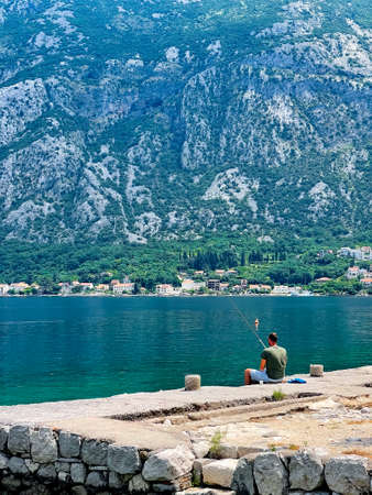 Fisherman on the shore of the Bay of Kotor in Montenegro, vertical photo