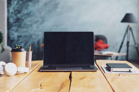 Closeup of laptop with blank monitor and cups, headphones, coffee on a table in a cafe. Freelancer home office.の写真素材
