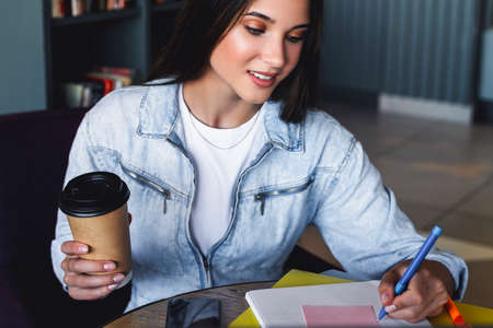 Millennial woman sits at a laptop and studies remotely. The student uses online distance learning opportunities. Women improve skills and knowledge through training. Young woman watching a webinar.の写真素材
