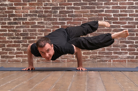 Sporty attractive young man working out, yoga, pilates, fitness training, asana Parshva bakasana...