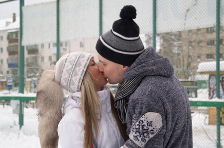 Young couple in love Caucasian man and beautiful woman have fun, active date ice skating on the ice arena in the city square in winterの写真素材