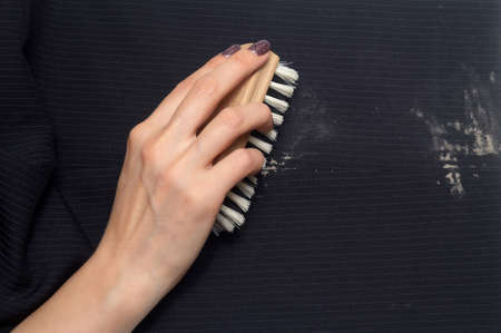 Dry cleaning: a woman hand with holding a clothes brush for cleaning clothes from dirty
