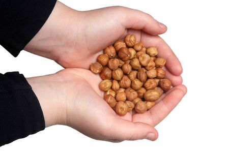Healthy eating, dieting, vegetarian food concept. Close up of kid hands holding peeled hazelnut on...